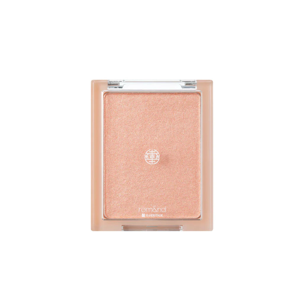 rom&nd See-Through Veil Lighter in a compact, showcasing its radiant peach shade with a shimmering finish.