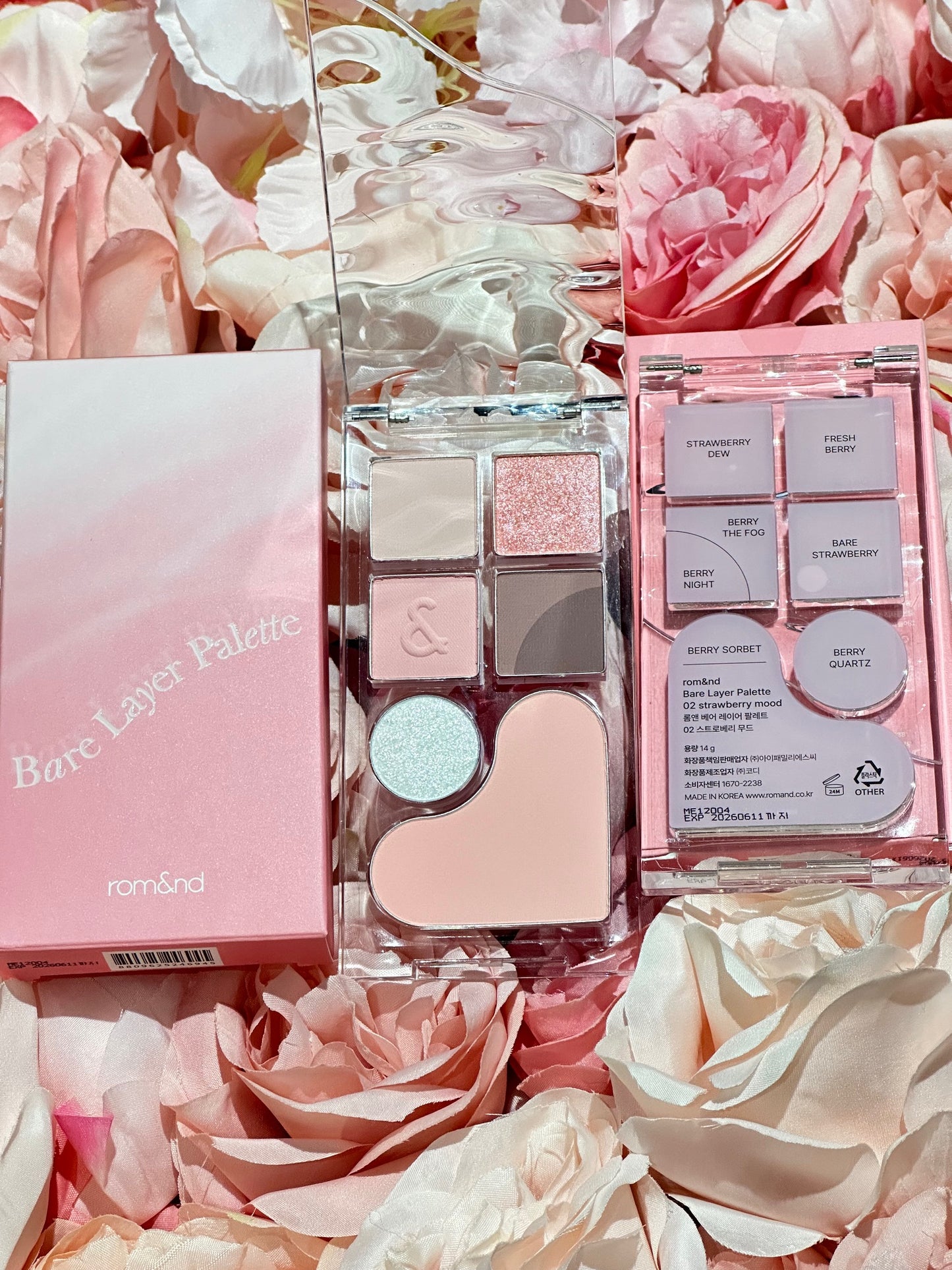 The rom&nd Bare Layer Mood Palette nestled among soft pink roses, highlighting the aesthetic charm of its Strawberry Mood design.
