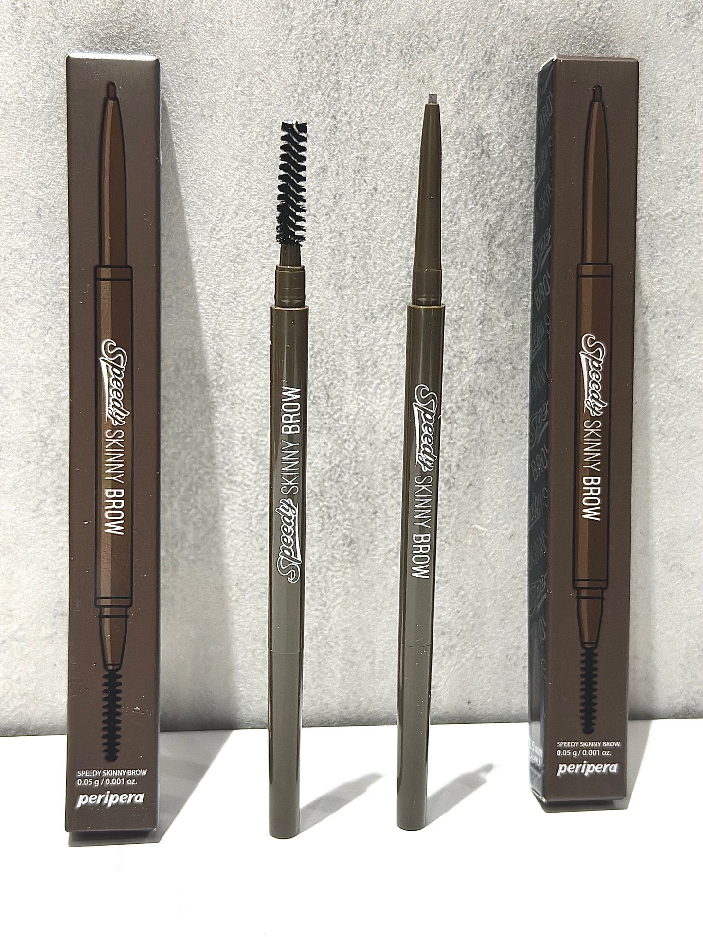 Peripera Speedy Skinny Brow pencil and packaging arranged stylishly, showcasing the product that promises precise eyebrow definition.