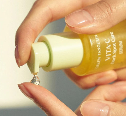 Close-up of a hand dispensing a drop of Goodal Vitamin C Serum from the bottle, ready to illuminate skin.