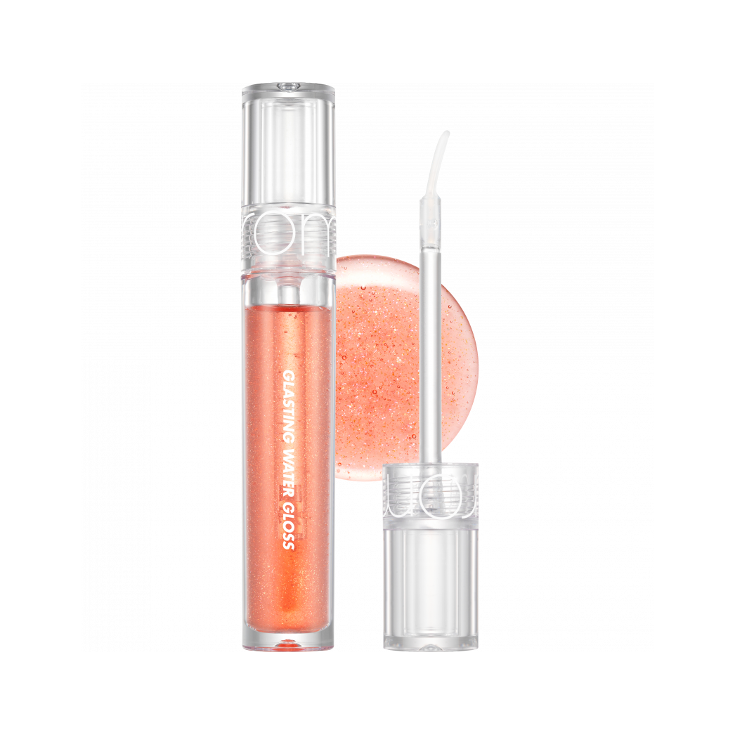 rom&nd Glasting Water Gloss in a shimmering soft peach shade, with a wand applicator and glistening gloss in the background.