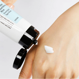 a person holding a tube of cream on their hand