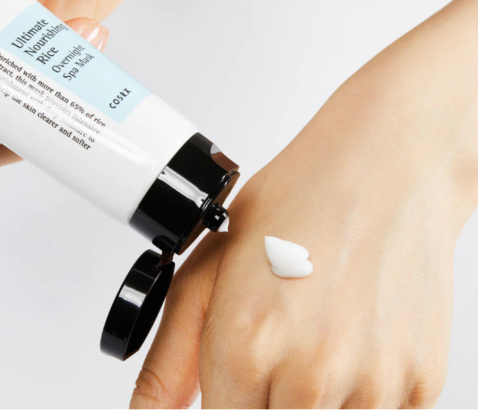 a person holding a tube of cream on their hand