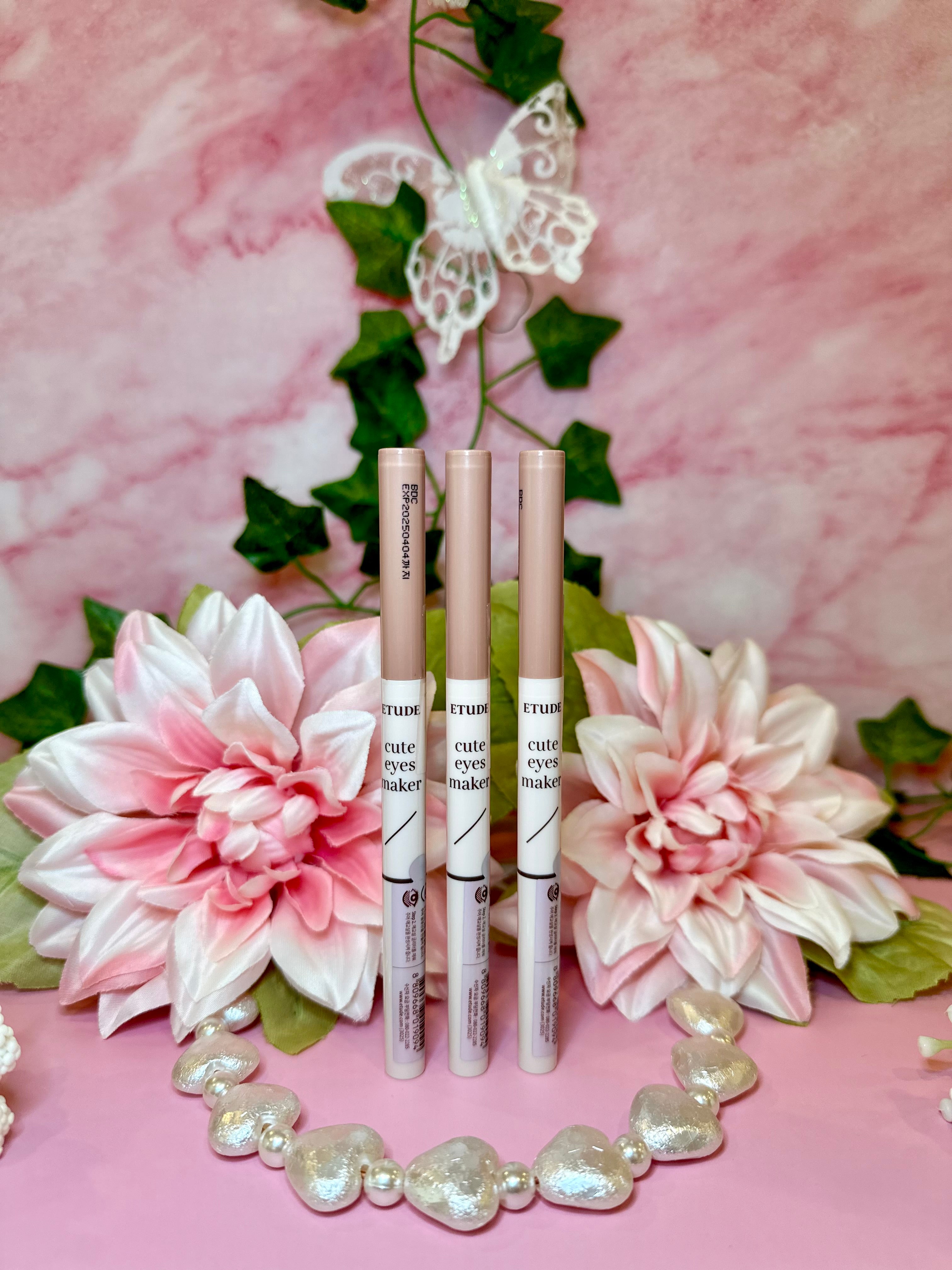 three lip glosses sitting on top of a pink table