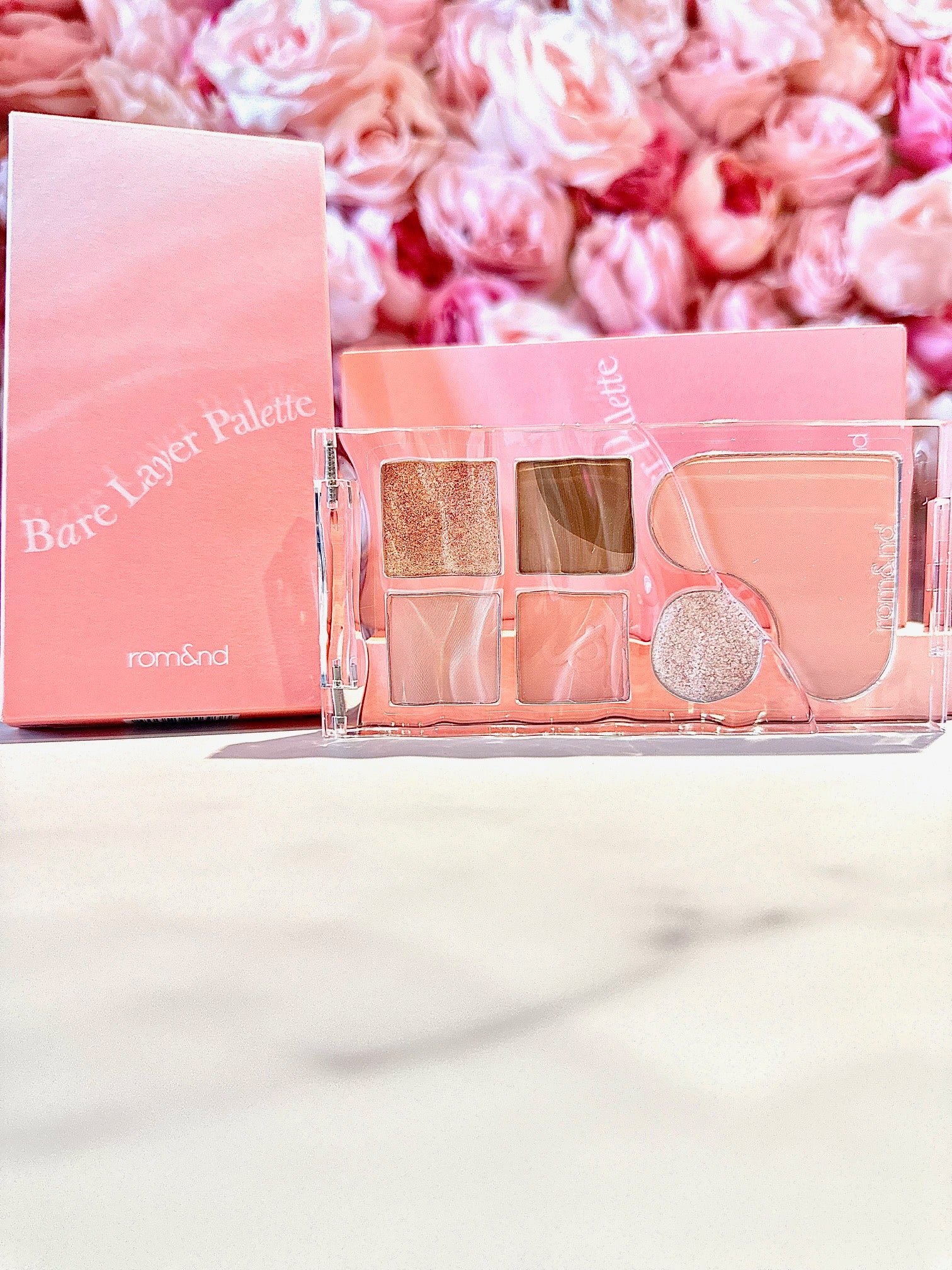 The rom&nd Bare Layer Mood Palette elegantly displayed with a charming pink background, showcasing its gorgeous shades for versatile looks.