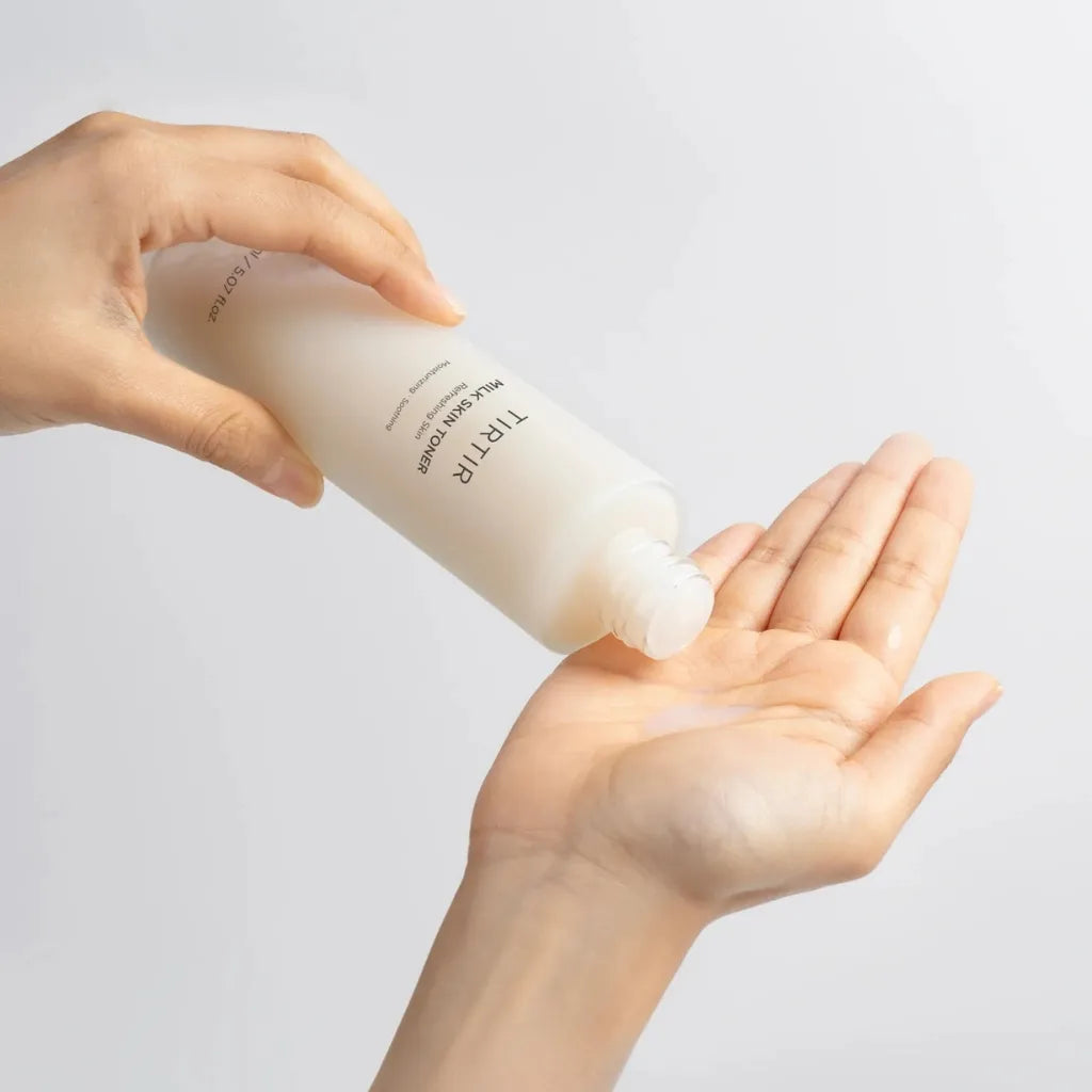 A hand pouring Tirtir Milk Skin Toner into an open palm, showcasing the toner’s rich and hydrating texture. Perfect for achieving glass skin.