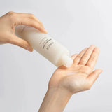A hand pouring Tirtir Milk Skin Toner into an open palm, showcasing the toner’s rich and hydrating texture. Perfect for achieving glass skin.