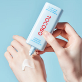 A hand applying Tocobo Bio Watery Sun Cream SPF50+ PA++++ on skin, demonstrating its light and moisturizing formula suitable for sensitive skin.