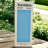 Torriden Dive In Serum box set against a natural outdoor backdrop, emphasizing the clean beauty aspect of the product.
