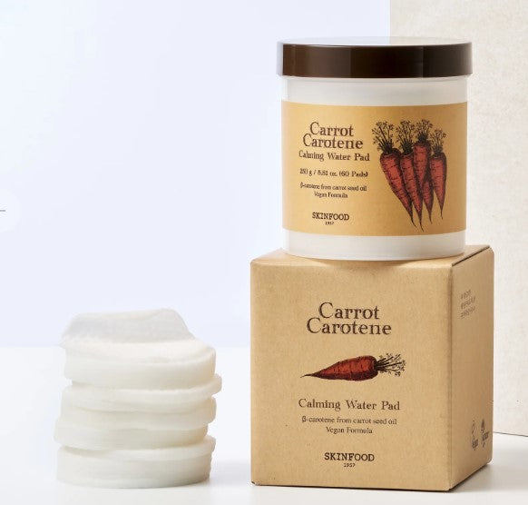 Skinfood Carrot Carotene Calming Water Pad packaging with cotton pads arranged beside it, showcasing its soothing properties for sensitive skin.