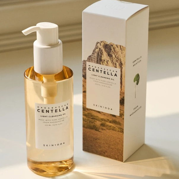 Skin1004 Madagascar Centella Light Cleansing Oil in a glass bottle with a pump, displayed next to its stylish box, ideal for removing makeup and impurities.