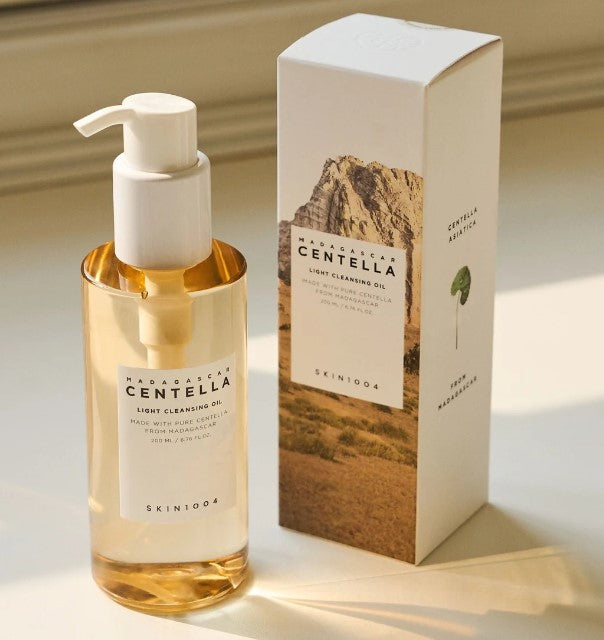 Skin1004 Madagascar Centella Light Cleansing Oil in a glass bottle with a pump, displayed next to its stylish box, ideal for removing makeup and impurities.