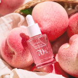 a bottle of pink liquid sitting on top of a pile of apples