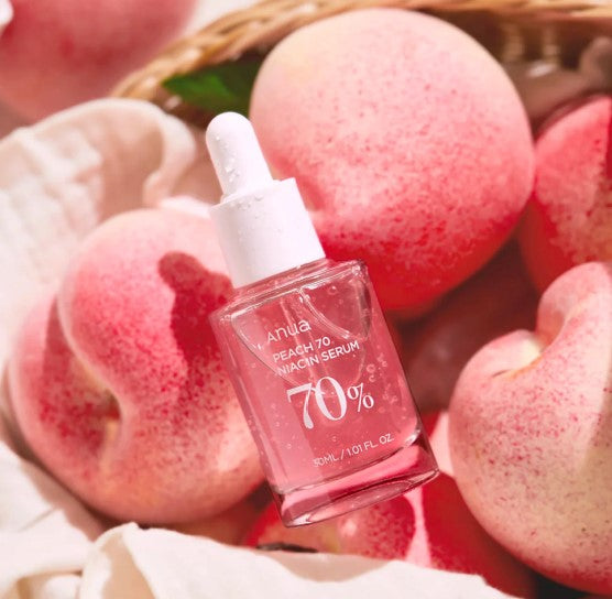 a bottle of pink liquid sitting on top of a pile of apples