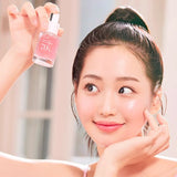 a woman holding up a bottle of pink nail polish