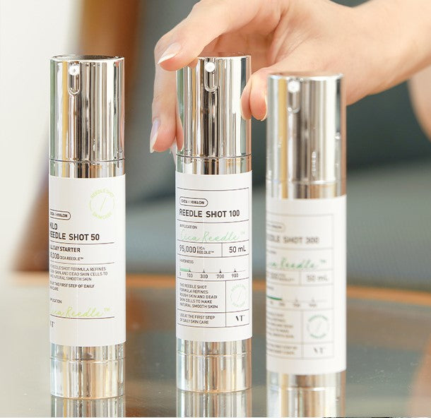 A hand holding VT Cosmetics Mild Reedle Shot 50, Reedle Shot 100, and another essence, showcasing the product range for comprehensive skin care.
