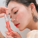 A beautiful moment with a model applying rom&nd Glasting Water Gloss, showcasing a luscious shade with shiny, plump lips.